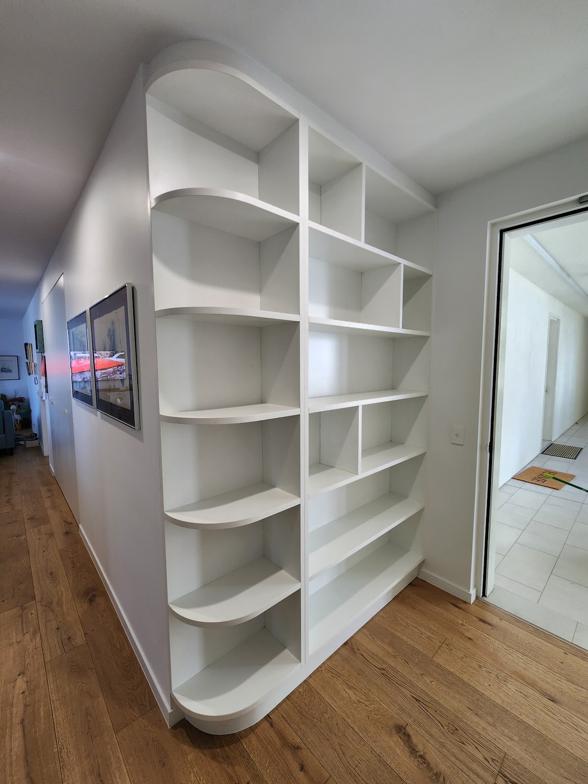 White built-in bookshelf with curved open ends in a hallway