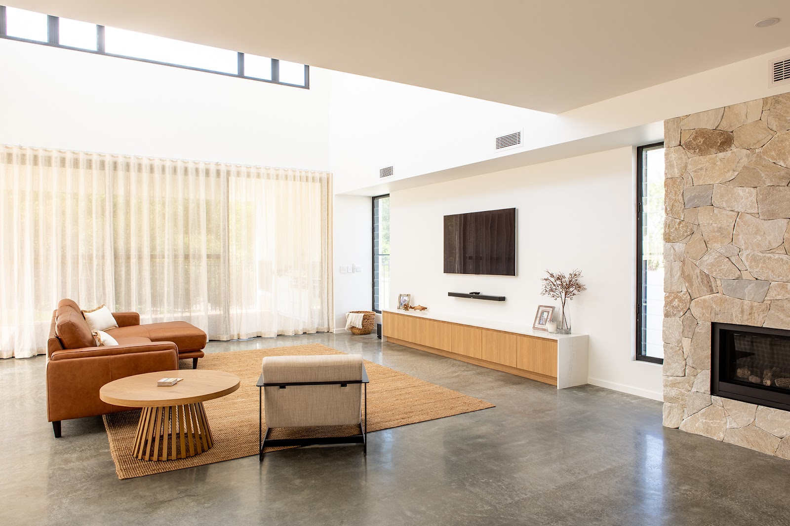 Living room with a long timber-look entertainment unit and stone fireplace