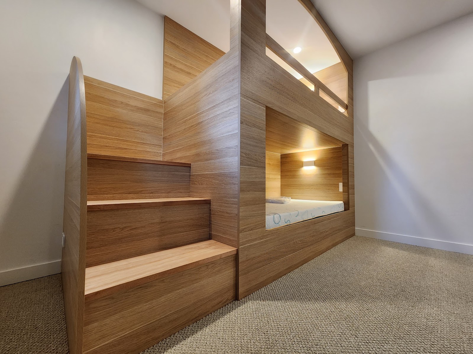 Custom timber built-in bunk beds with stair drawers and reading lights