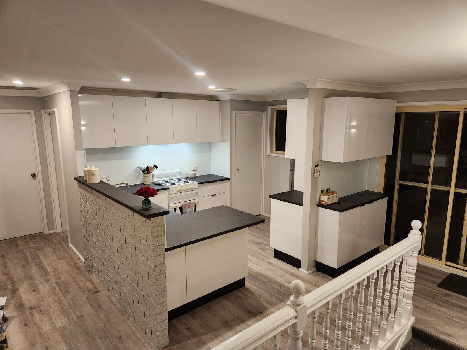 Gloss white kitchen with dark benchtops, an island and a breakfast bar